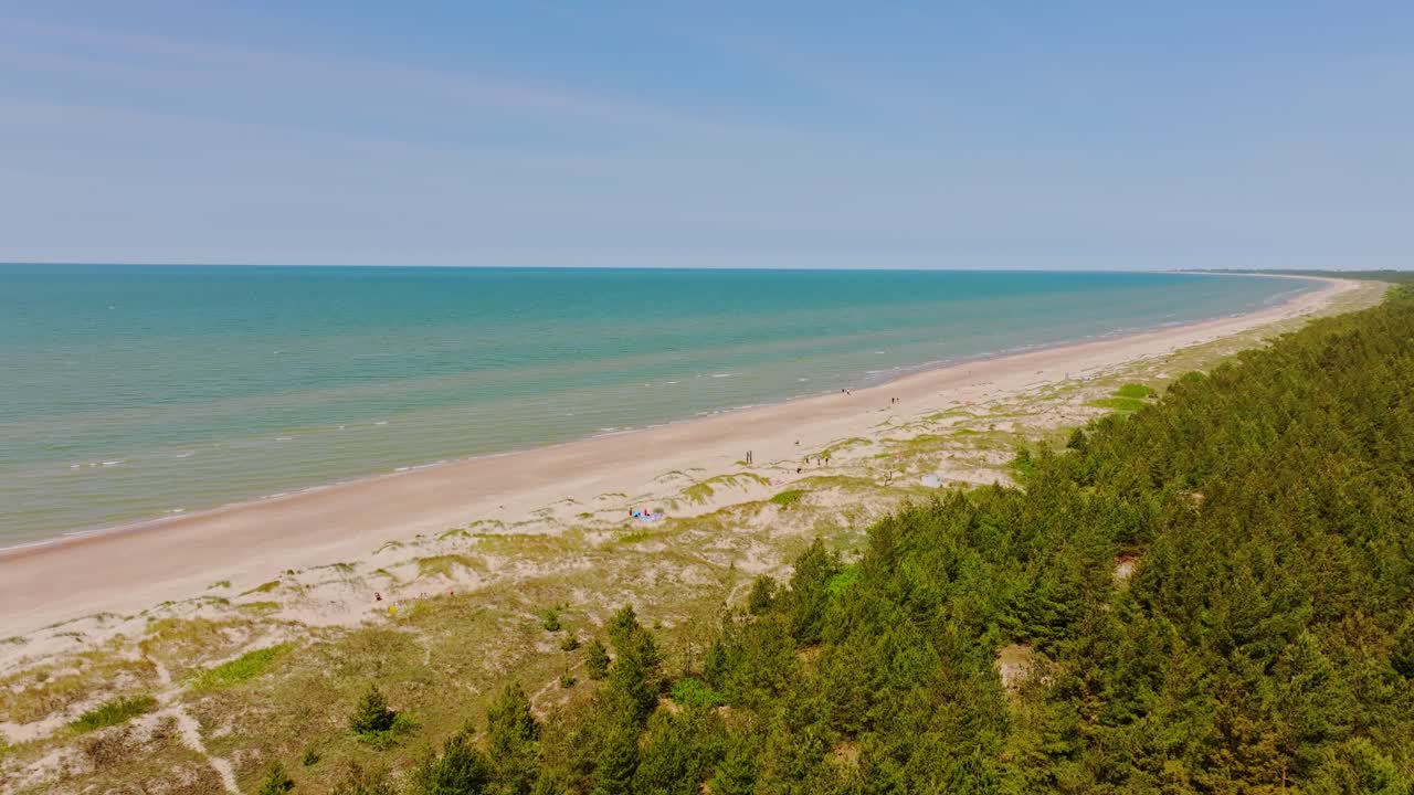 Pērkone coastline stretches with blue sea, beach dunes and pine forest revealed