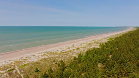 pērkone coastline stretches with blue sea, beach dunes and pine forest revealed
