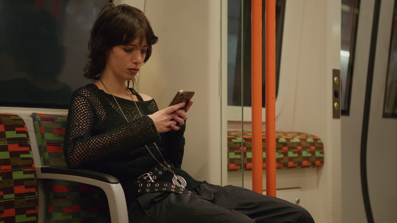 Shot Of Alternative Style Woman Using Mobile Phone Sitting On London Underground Train In Real Time 1