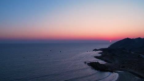 puesta de sol sobre un mar tranquilo con siluetas de montañas
