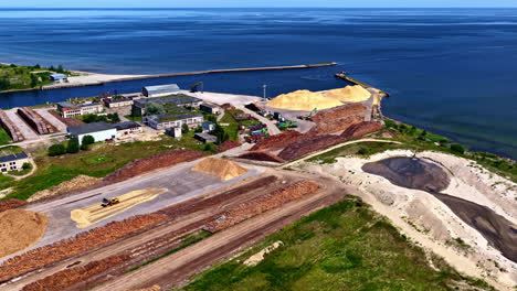 mērsrags port in latvia, a busy industrial harbor and logistics terminal for exporting timber and wood chips, situated on the scenic baltic sea coast - wide aerial drone shot