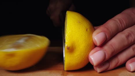 mujer cortando un limón en la tabla de cortar. limón en rodajas a mano en la mesa de cortar de cerca