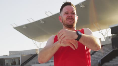atleta masculino caucásico estirándose antes de correr en un día soleado