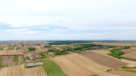 Panorama-Of-Agricultural-Land-With-Meadow-Field-And-Wind-Turbine-Near-Villages