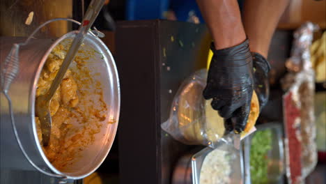 Vertical-slow-motion-of-a-latin-male-hands-with-black-latex-gloves-preparing-serving-a-taco-of-chicharron-with-salsa-at-a-traditional-mexican-restaurant