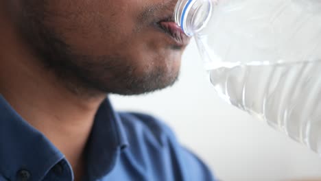 a man drinking water from a plastic bottle