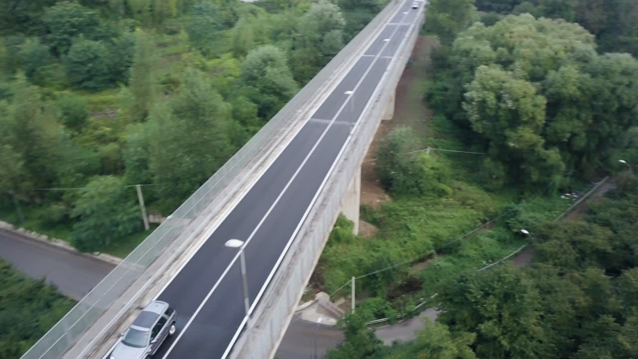 toma de un dron de un land rover en una carretera rodeada de árboles
