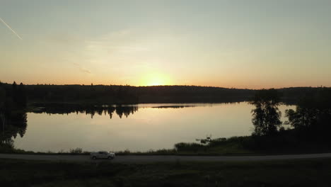 Camiones-Conducen-A-Lo-Largo-Del-Lago,-Borde-Del-Bosque-Boreal,-Saskatchewan-Al-Atardecer