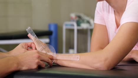 male therapist measuring female patient hand with goniometer