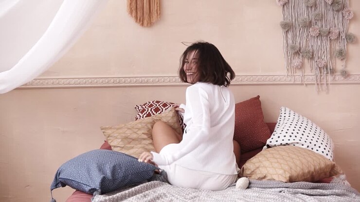 Un filmato di una bellissima giovane donna che corre e si getta sul letto in un elegante costume bianco, mentre fa una capriola.