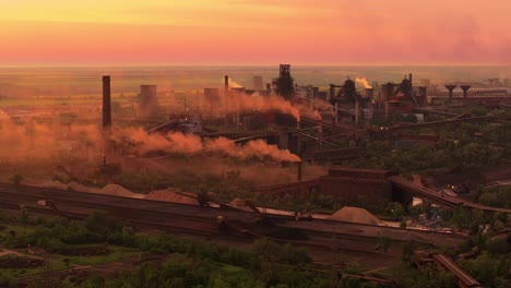 Industrial-smokestacks-with-smoke-emissions,-against-the-vivid-hues-of-orange-sunlight,-high-contrast