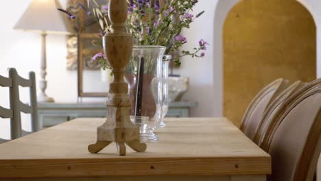 dining room table with flower vases and different set chairs on sides at a villa in southern france, dolly right close up shot