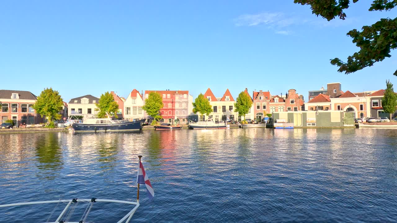 Moving boat view of Haarlem canal, Dutch houses, calm water, bright daylight, gentle camera pan
