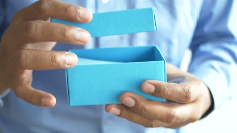 men open a blue  box and reading a message in a note,