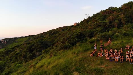 aerial rotation drone shot of people watching sunrise on mountain in florianopolis, brazil