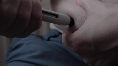 primer plano de la autoaplicación del medicamento a través de una pluma de aguja médica inyectando la sustancia en un área grasa del abdomen dejando una marca de una gota de sangre