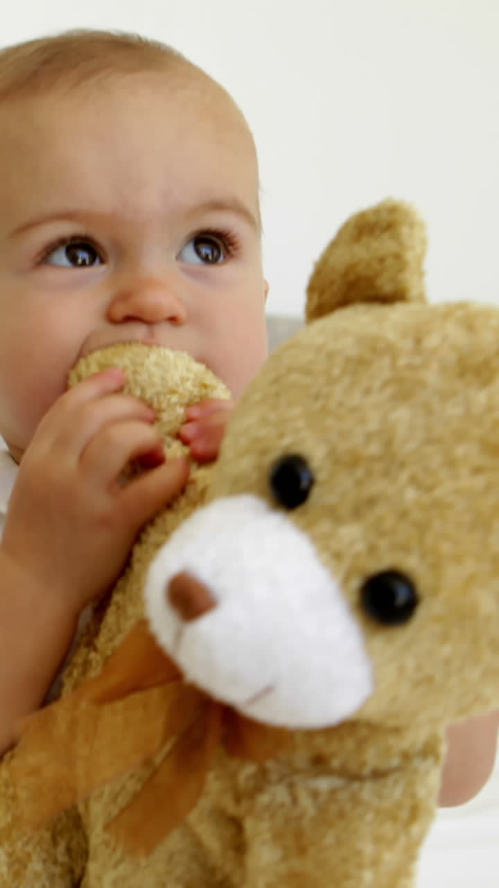 Tierna niña bebé jugando con un oso de peluche en la cama.
