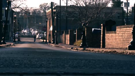 A-Man-Crossing-The-Streets-Of-Haddonfield,-New-Jersey-In-The-Distance-On-A-Bright-Morning---Static-Shot