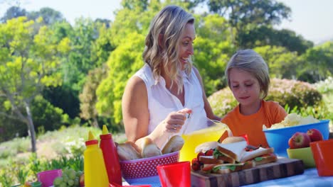 madre feliz vierte jugo de naranja a su hijo en el parque 4k