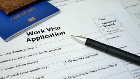 work visa application form with passport and pen