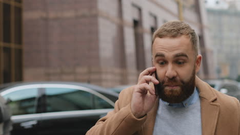 close-up view of angry caucasian man in elegant clothes walking on the street and talking on the phone