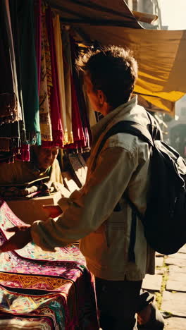 man looking at textiles in an outdoor market