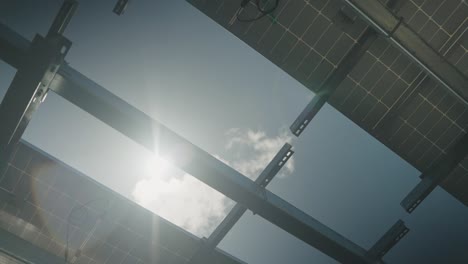 bottom up shot of solar panels silhouette and sunlight with blue sky in background