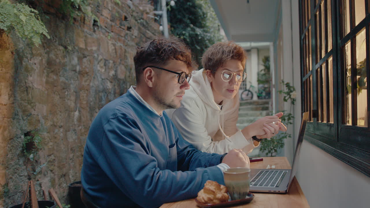 Coworkers Discussing Something on Laptop in a Small Patio