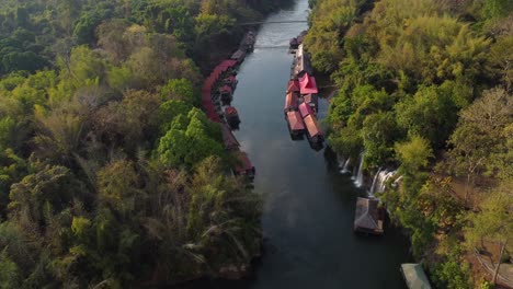 Un-Dron-Giratorio-De-Un-Río-En-Medio-De-La-Jungla,-Con-Cascadas-Y-Un-Pueblo-Flotante-A-Un-Lado-Del-Río