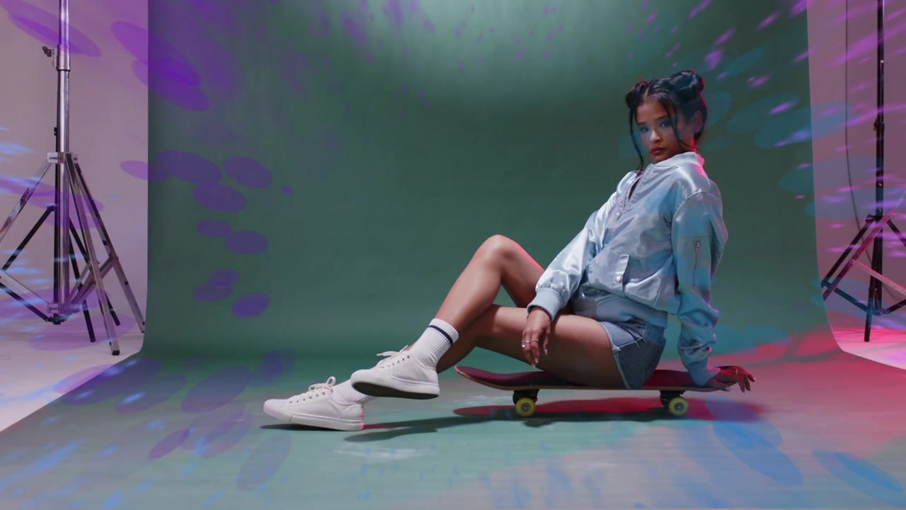 Model sidder på skateboard i studie, optagelse starter med en lilla-blå ring, der cirkler rundt om hende og derefter forsvinder.