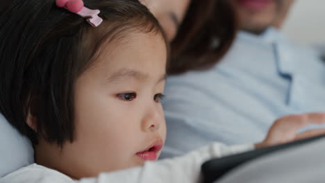 Süßes-Kleines-Asiatisches-Mädchen,-Das-Einen-Tablet-Computer-Benutzt,-Während-Die-Familie-Spiele-Auf-Einem-Touchscreen-Gerät-Spielt-Und-Sich-Zu-Hause-Zusammen-In-4K-Entspannt