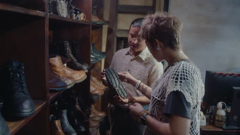 vintage store salesman telling about leather boots to woman