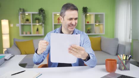 el trabajador de la oficina en casa que lee el documento en su mano está encantado.