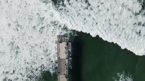 Grandes-Olas-Rompiendo-Bajo-Una-Plataforma-Peatonal-De-Hormigón-Construida-En-El-Océano