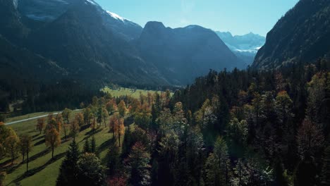 Colorful-vibrant-maple-trees-with-red-and-yellow-fall-leaves-in-sunny-autumn-in-the-alps-mountains-in-Tyrol,-Austria-at-scenic-Ahornboden-forest-at-Rissach-Engtal-with-blue-sky