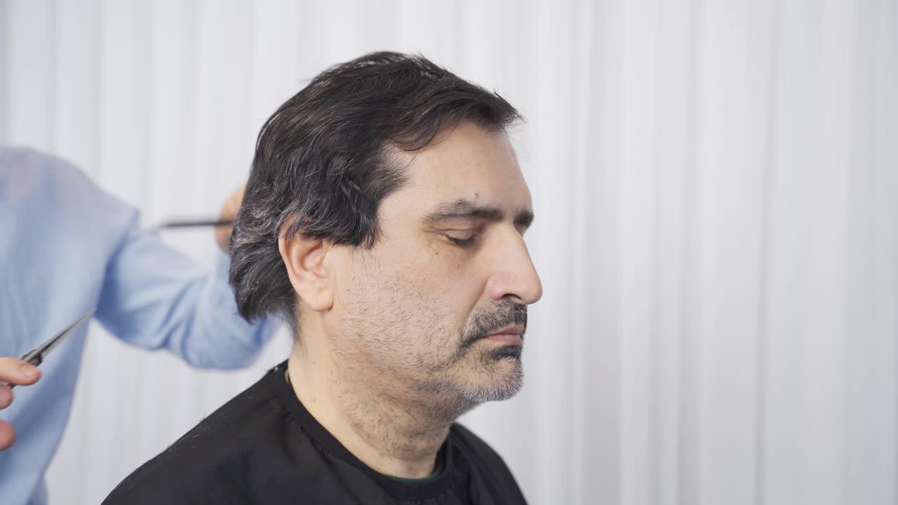 The sick man's hair is being shaved at home. Patient care service.
