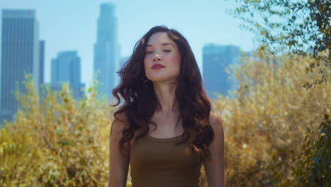 woman looking back on skyscrapers standing in park. asian lady enjoy city view.