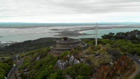 people at bluff hill lookout with ocean and landscape in the background on cloudy day - new zealand - aerial drone