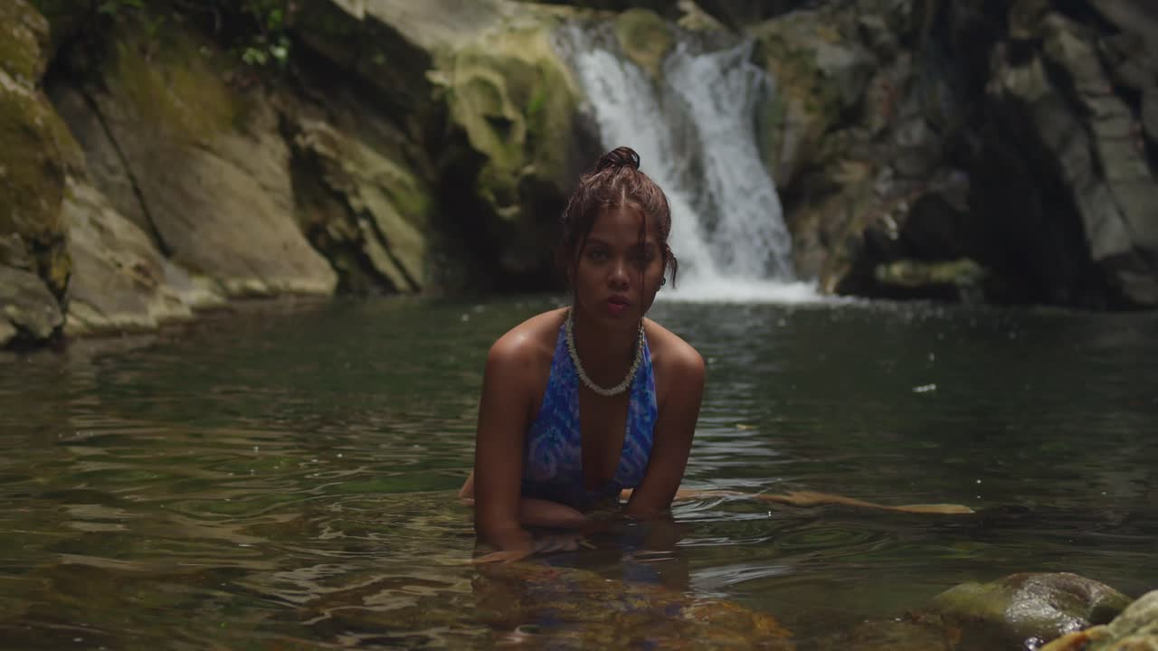Una giovane ragazza in bikini si gode la cascata e il fiume sull'isola tropicale di Trinidad