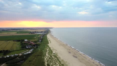 Static-aerial-shot-of-beach-with-fishing-village-on-the-coast-of-Norfolk,-UK