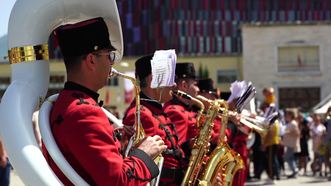 Brass band in red uniforms performing musical parts in square of Tirana capital city
