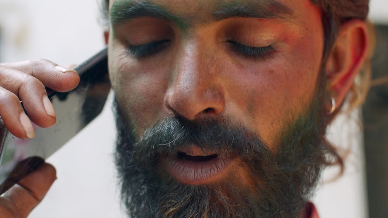 hombre indio de primer plano de la cara manchada con colores brillantes de holi