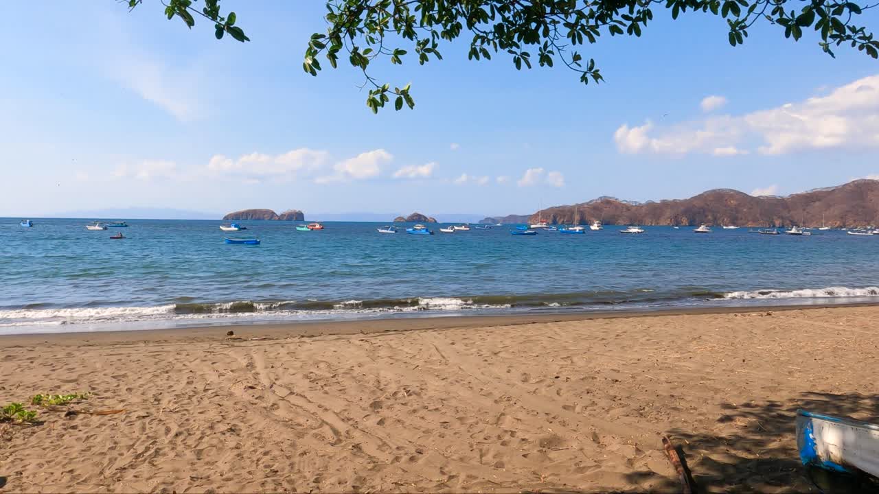 bote de madera en una playa tropical con un árbol viejo en un día soleado, playa coco en guanacaste, costa rica