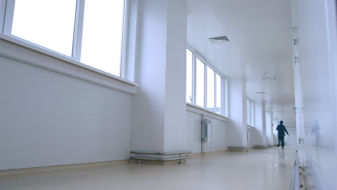 Woman in uniform running in white corridor back view. Urgent work