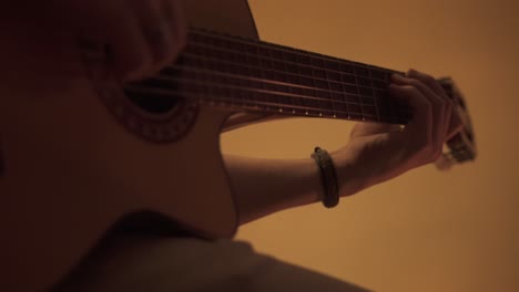 close up of musician playing acoustic guitar indoors at concert - tracking shot