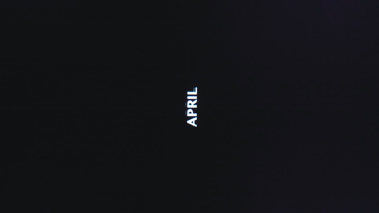 Parola verticale 'Aprile' con glitch in lettere maiuscole su sfondo scuro retrò VHS.