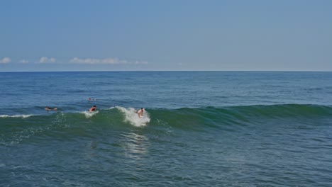 Aerial:-surfer-paddling-and-catching-wave-off-Mexican-Pacific-coast,-follow-view