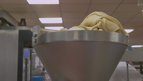 pastry gradually and slowly moves down into the funnel of a pastry press in a factory setting