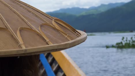 traditional myanmar bamboo hat on person boating across inle lake