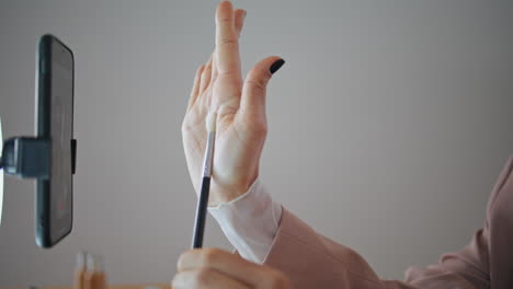 blogger hand showing brush smartphone at apartment closeup. woman recording blog